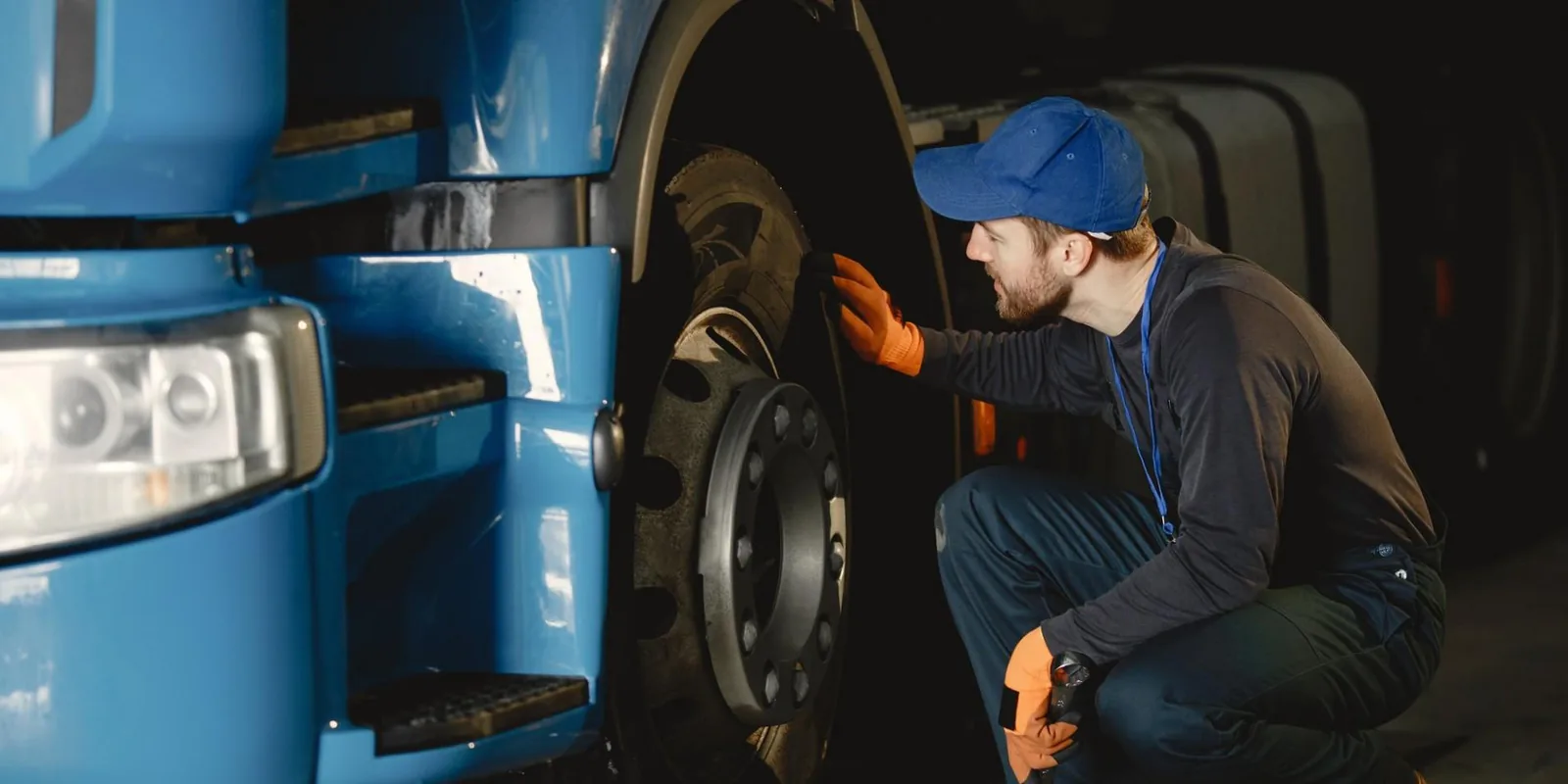 Inspector crouched at the wheel end of a commercial truck checking the brake during a roadside inspection